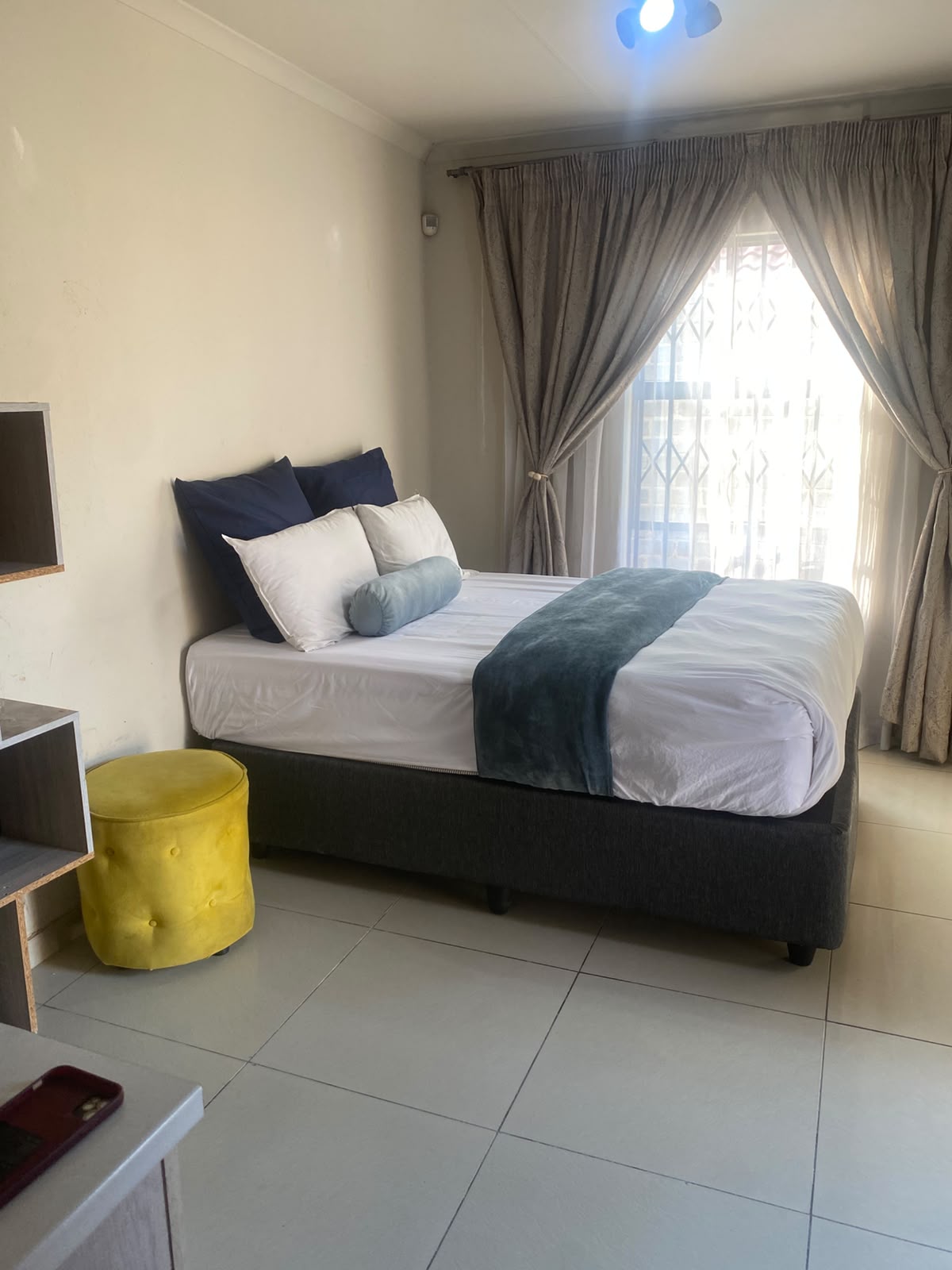Room 7 at Bahumi Guesthouse 2 with double bed, navy pillows and yellow stool